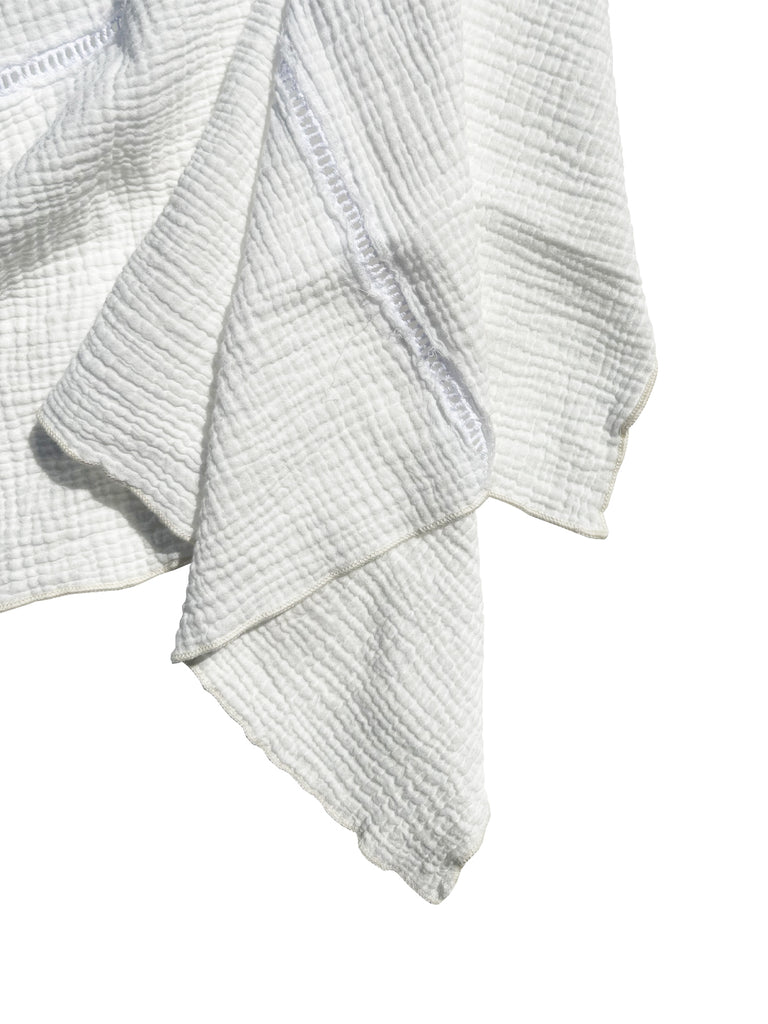 A close of of the edge and corner area of the hung dish towel against a white background