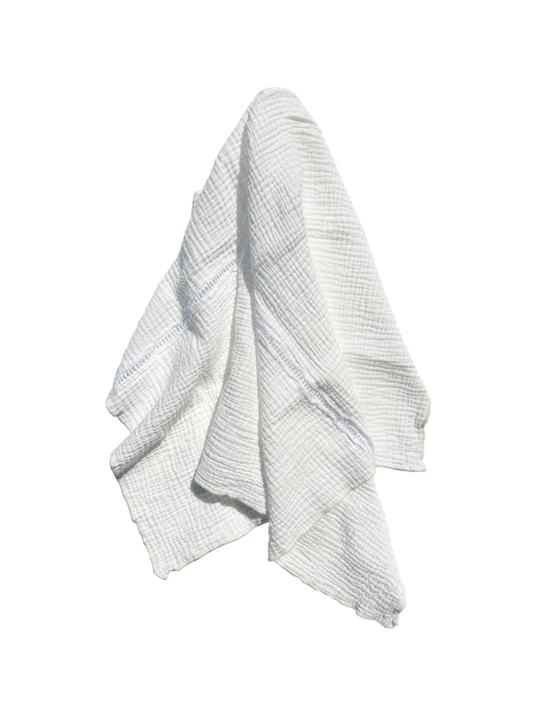A white slightly soft looking textured dish towel hung against an all white background